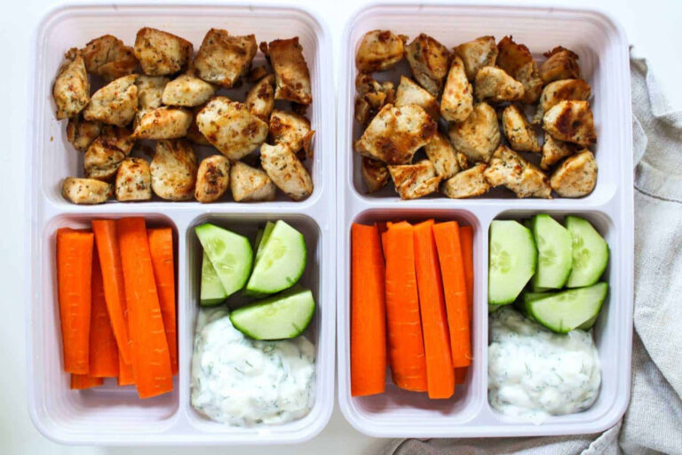 Meal prep container with chicken, cucumber, carrots, and dipping sauce